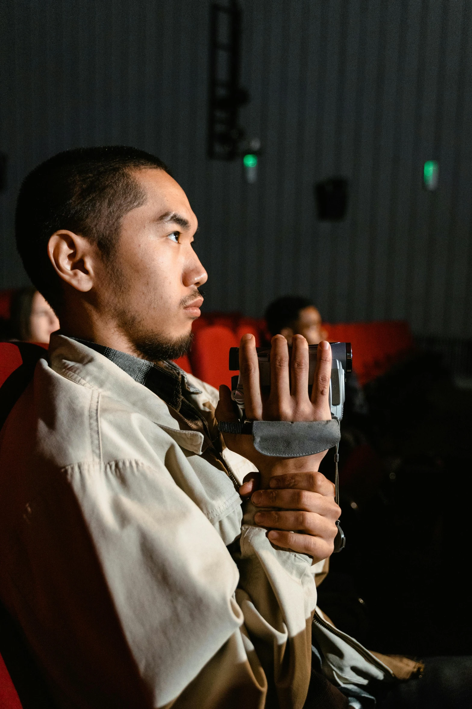 a man sitting in a movie theater holding a remote control, visual art, thawan duchanee, holding arms on holsters, prosthetic arm, headshot