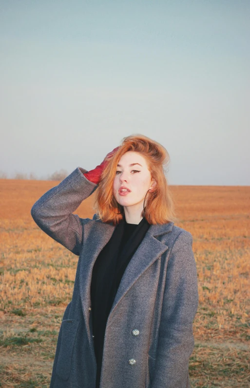 a woman standing in the middle of a field, trending on pexels, ginger hair and fur, very pale white skin, wearing a black jacket, vintage aesthetic