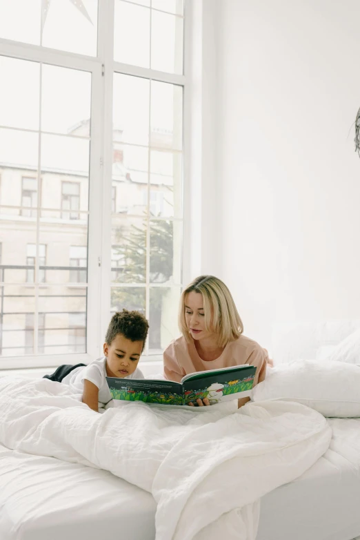 a woman reading a book to a child on a bed, profile image, big windows, family photo, instagram photo