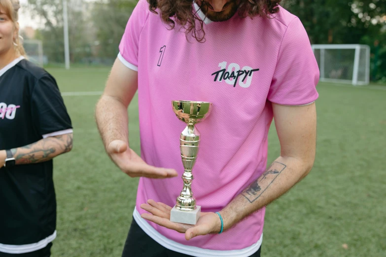 a man in a pink shirt holding a trophy, by Jacob Toorenvliet, dribble contest winner, tripy, clip stadio, wearing a t-shirt, medium close-up shot