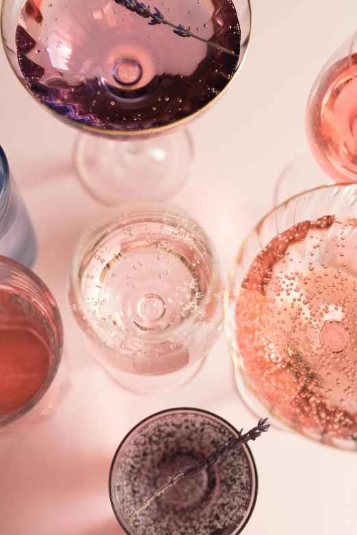 a group of wine glasses sitting on top of a table, by Carey Morris, trending on unsplash, renaissance, pink, lots of bubbles, shot from above, detailed product shot