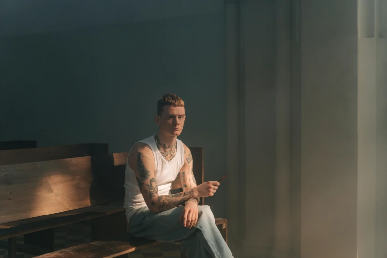 a man sitting on top of a wooden bench, a tattoo, by Elsa Bleda, pexels contest winner, bauhaus, james jean soft light 4 k, lil peep, portrait soft light, sitting in a lounge