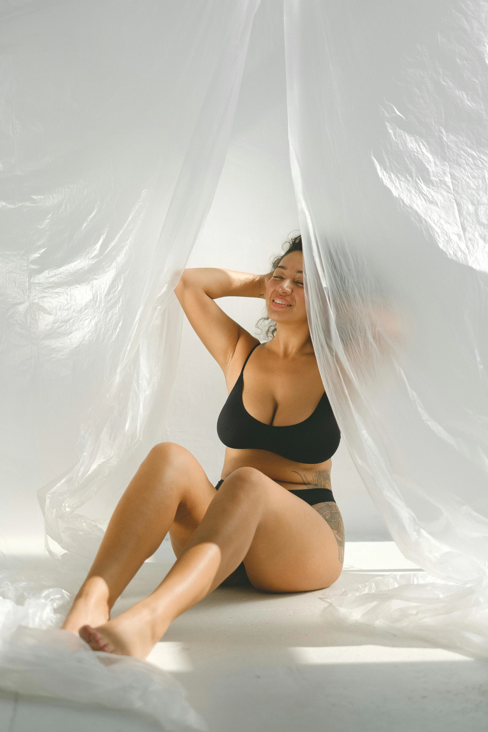 a woman sitting on top of a bed covered in plastic, inspired by Herb Ritts, unsplash, plasticien, fit curvy physique, lined in cotton, profile image, profile pic