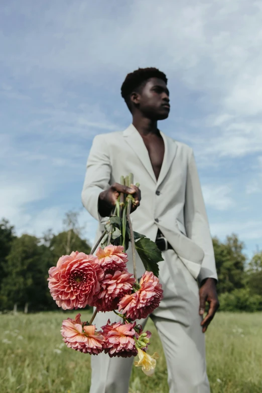 a man standing in a field holding a bunch of flowers, by Carey Morris, pexels contest winner, man is with black skin, off - white collection, delicate androgynous prince, professional modeling