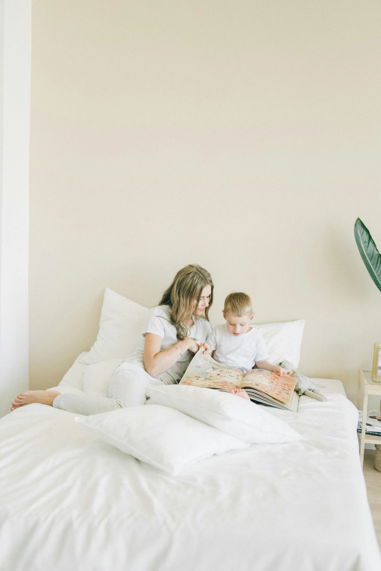 a woman reading a book to a child on a bed, pexels contest winner, clean minimalist design, dwell, white, promo image