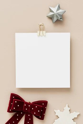 a piece of paper sitting on top of a table next to a snowflake, flatlay, 144x144 canvas, white space, thick bow