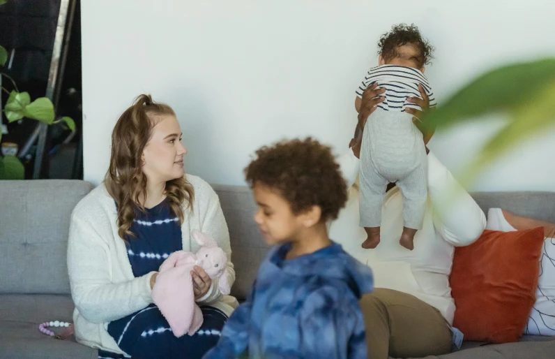 a woman and a child sitting on a couch, families playing, diverse outfits, promo image, blurry