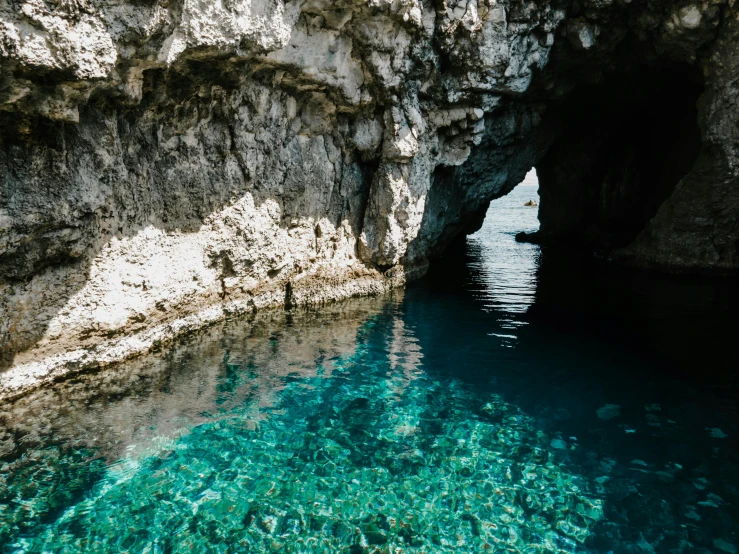 a cave in the middle of a body of water, clear blue water, canva, thumbnail