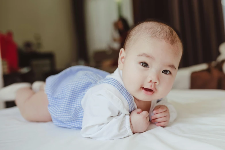 a baby laying on top of a bed next to a teddy bear, by Bernardino Mei, pexels contest winner, happening, young cute wan asian face, well - dressed, gif, son