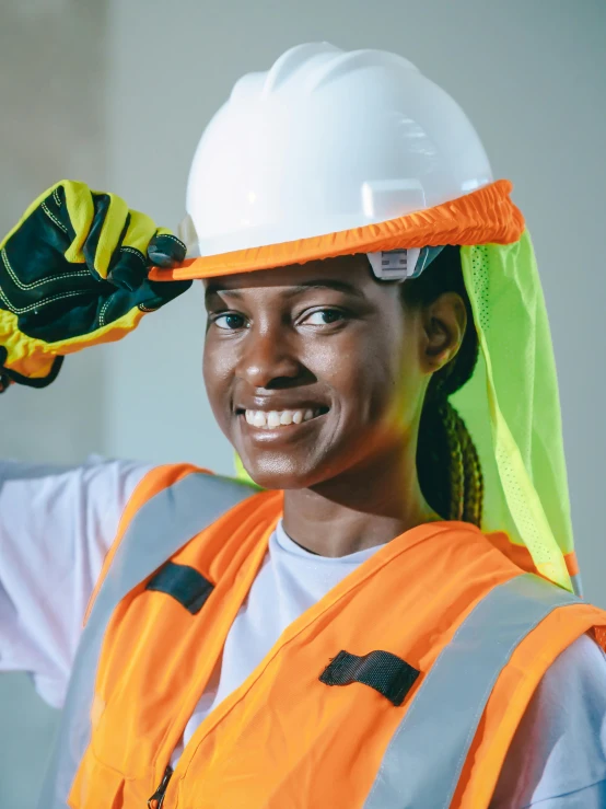 a woman wearing a hard hat and safety vest, inspired by Afewerk Tekle, pexels contest winner, hand holding cap brim, friendly face, educational, colorful uniforms