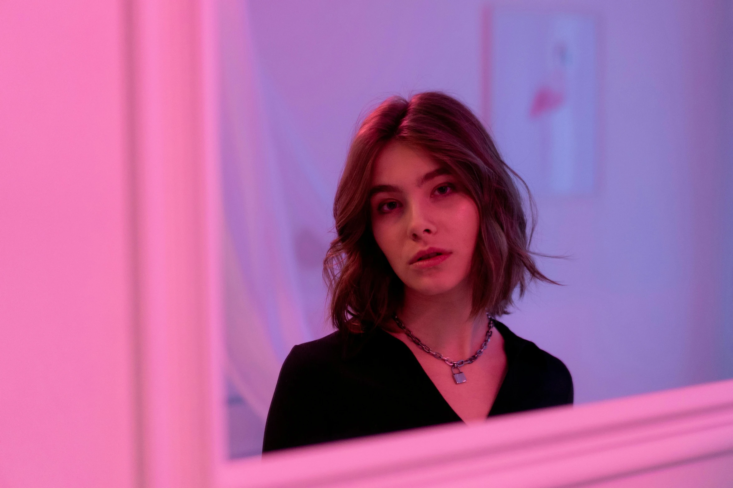 a woman looking at herself in a mirror, an album cover, inspired by Elsa Bleda, trending on pexels, realism, pink violet light, madison beer girl portrait, cyber necklace, looking at the ceiling