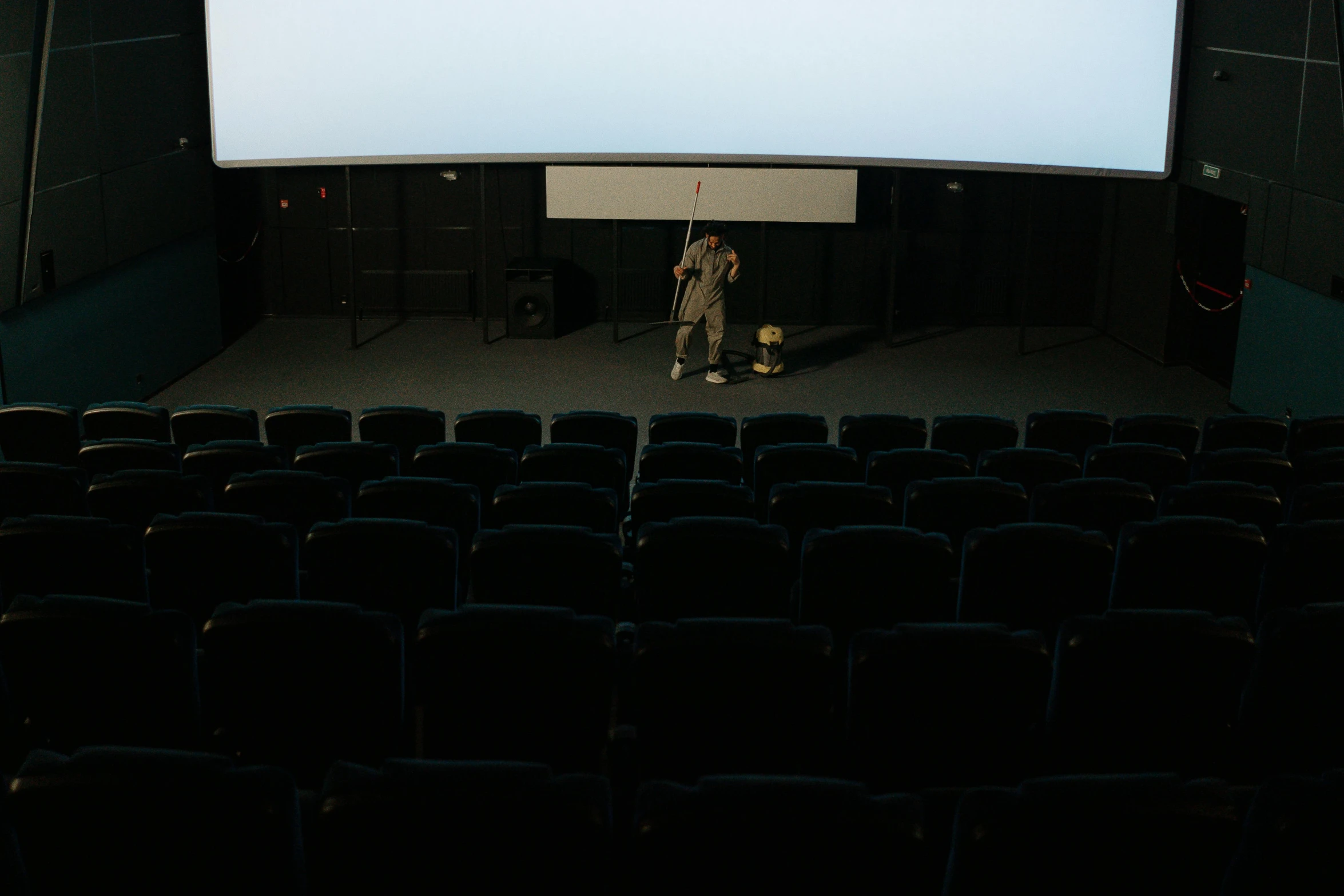 a man standing in front of a projection screen, photo of the cinema screen, deserted, full room view, cinestill