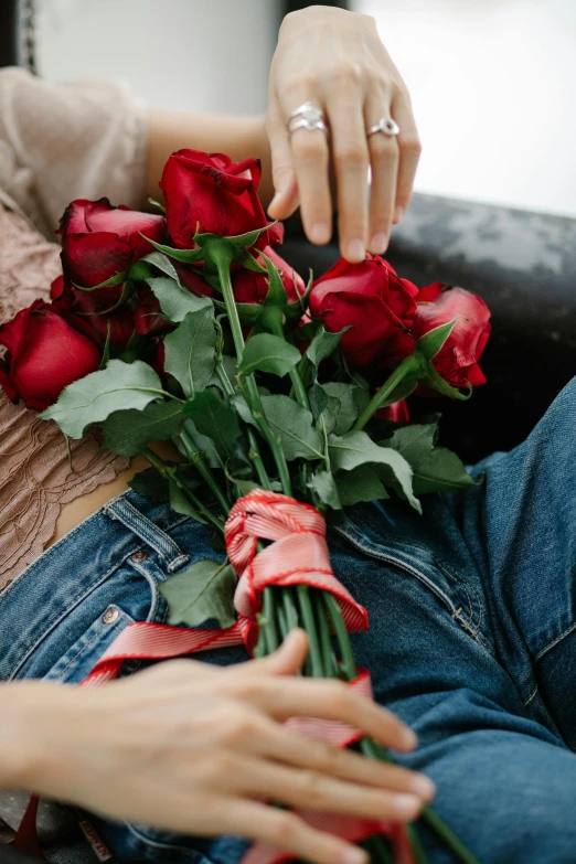 a woman laying on a couch holding a bunch of roses, inspired by Elsa Bleda, trending on unsplash, romanticism, jeans, red ribbon, hearts, teenage boy