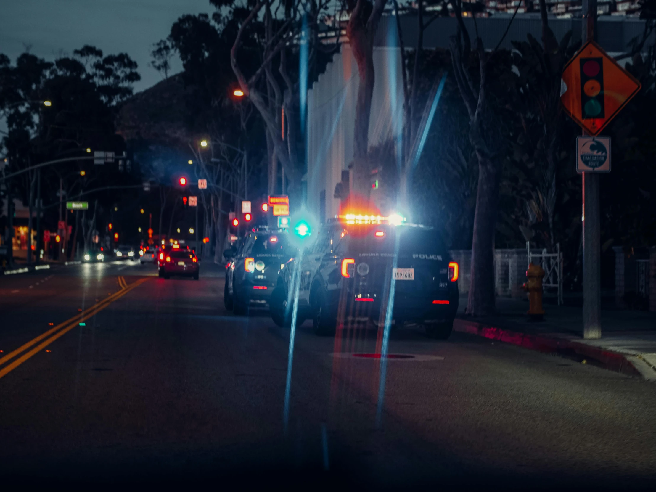 a group of cars driving down a street at night, police cars, background image, oceanside, injured