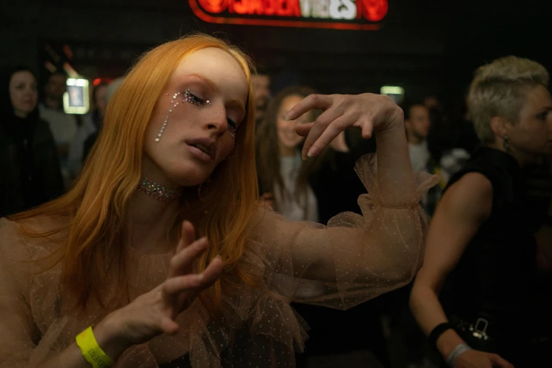 a woman standing in front of a crowd of people, an album cover, inspired by Elsa Bleda, pexels, renaissance, antichrist dancing at studio 54, freckles on chicks, college party, lily frank