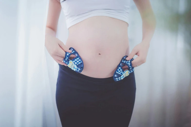 a pregnant woman in a white shirt and black skirt, by Julia Pishtar, pexels contest winner, happening, blue undergarments, patterned, diaper-shaped, pouches