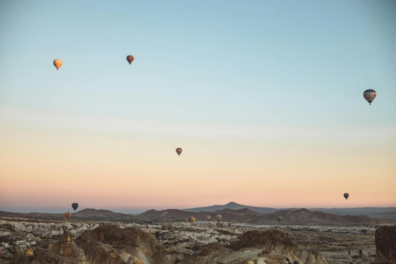 a group of hot air balloons flying in the sky, a matte painting, unsplash contest winner, in egypt, pale beige sky, three views, cyprus