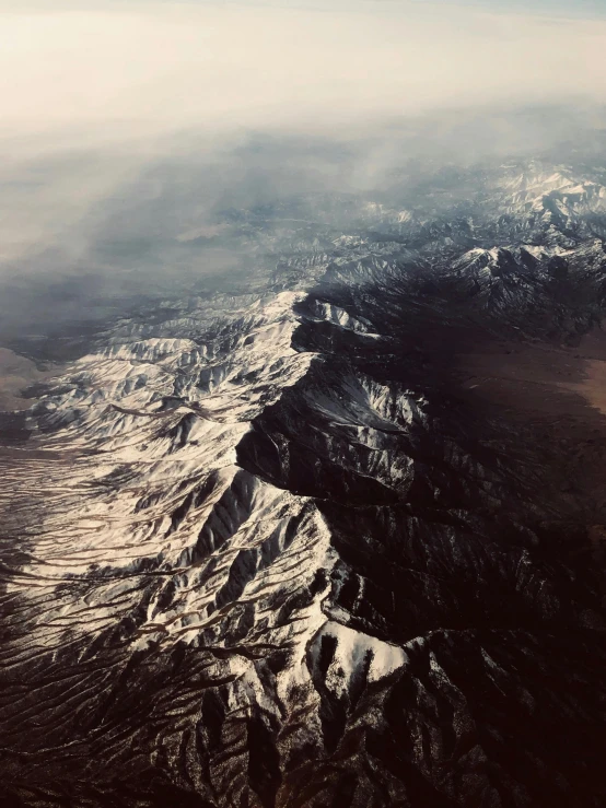 an aerial view of a snowy mountain range, pexels contest winner, erosion algorithm landscape, airplane window view, mojave desert, dark