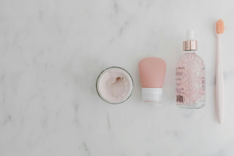 a couple of toothbrushes sitting on top of a counter, by Emma Andijewska, trending on pexels, minimalism, rose quartz, jar on a shelf, skin care, on a cloudy day