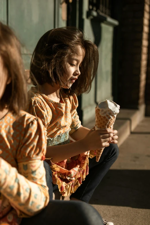 two young girls sitting on the sidewalk eating ice cream cones, pexels contest winner, process art, patterned clothing, perfectly lit. movie still, ( ( theatrical ) ), warm light