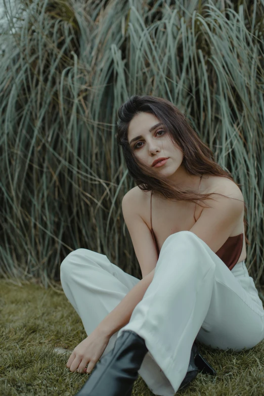 a woman sitting on top of a lush green field, an album cover, inspired by Elsa Bleda, trending on pexels, photorealism, madison beer girl portrait, white pants, professionally color graded, portrait of ana de armas