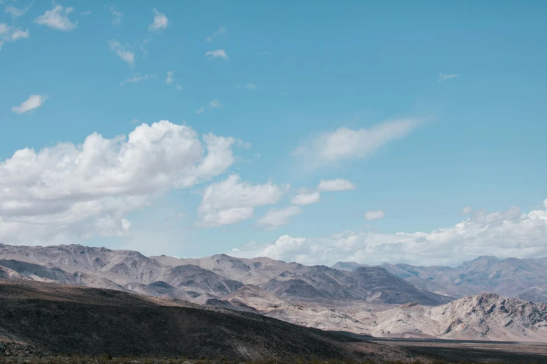 a man flying a kite on top of a lush green field, trending on unsplash, les nabis, road california desert, background image, mountain scape. film still, high clouds