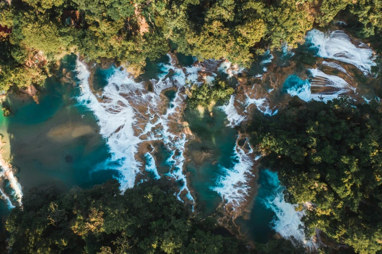 a river flowing through a lush green forest, an album cover, pexels contest winner, hurufiyya, blue waters, aerial photography, avatar image, magma cascades