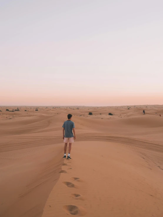 a man standing in the middle of a desert, pexels contest winner, arabian nights, slightly tanned, facing away, sandy colours