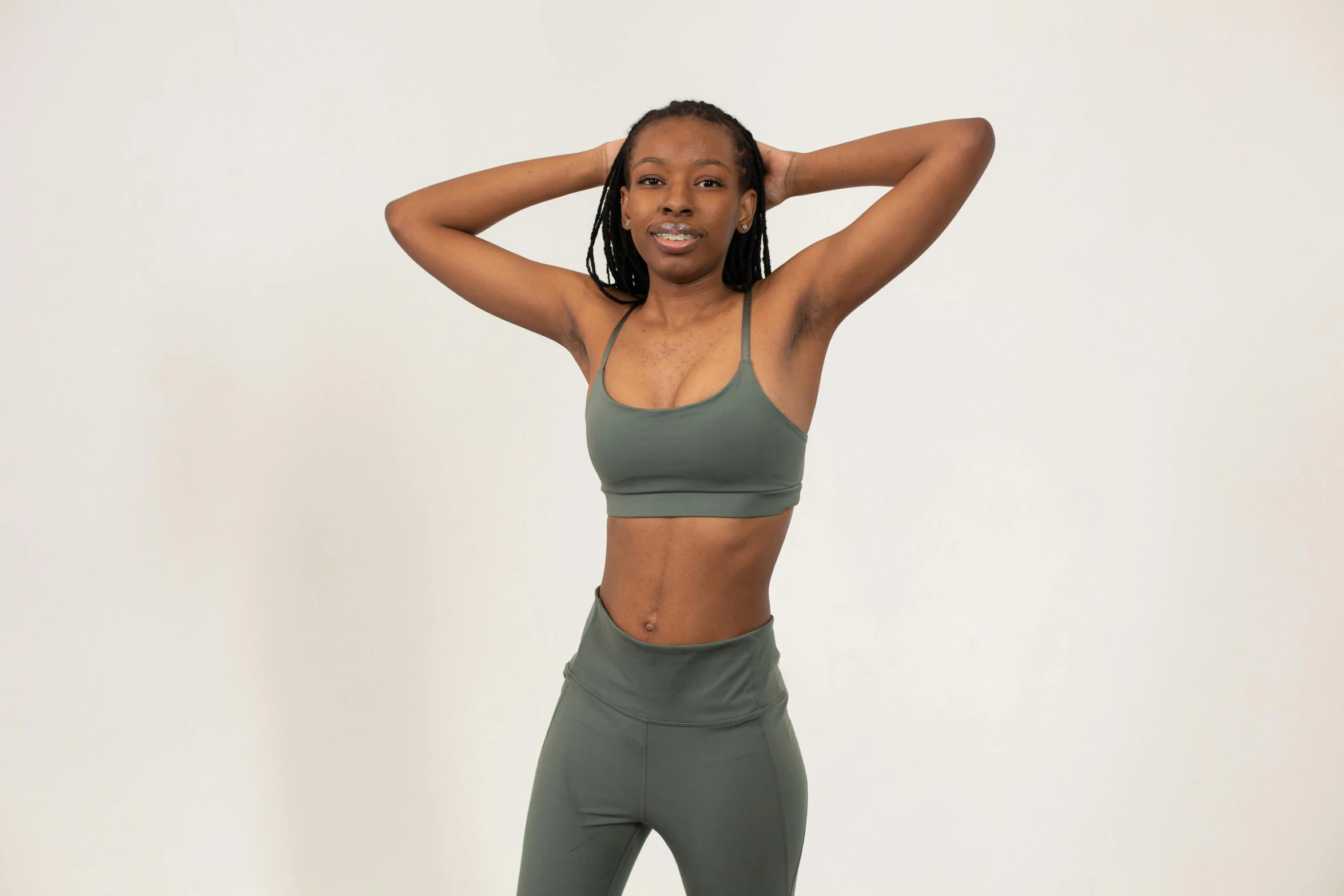 a woman in a sports bra top and leggings, pexels contest winner, muted green, dark skin tone, set against a white background, upper body image