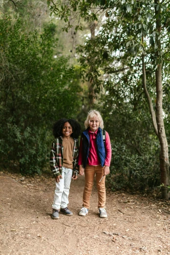 a couple of kids standing next to each other on a dirt road, green and brown clothes, bay area, in woods, splento
