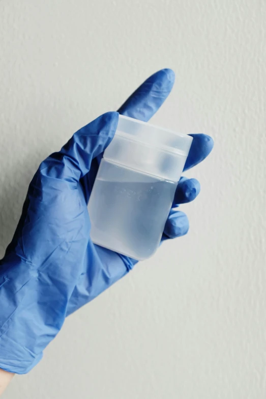 a person in blue gloves holding a plastic container, by Ryan Pancoast, soft opalescent membranes, high samples, promo image, in liquid