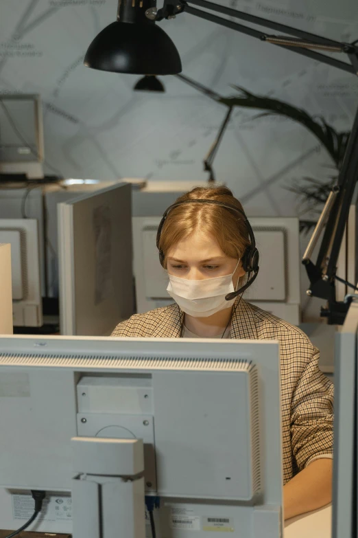 a woman wearing a face mask working on a computer, floating headsets, incompetent, slightly pixelated, sitting at a control center