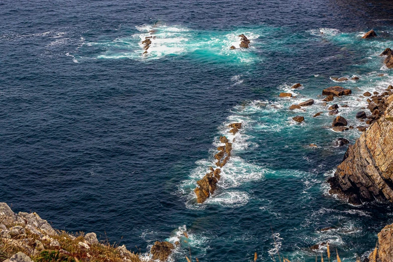 a group of people standing on top of a cliff next to the ocean, by Tom Wänerstrand, pexels contest winner, les nabis, island in a blue sea, scylla and charybdis, chile, texture