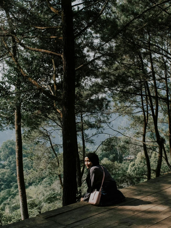 a man sitting on top of a wooden platform, a picture, unsplash contest winner, sumatraism, pine trees in the background, panoramic view of girl, 😭 🤮 💕 🎀, on a green hill between trees