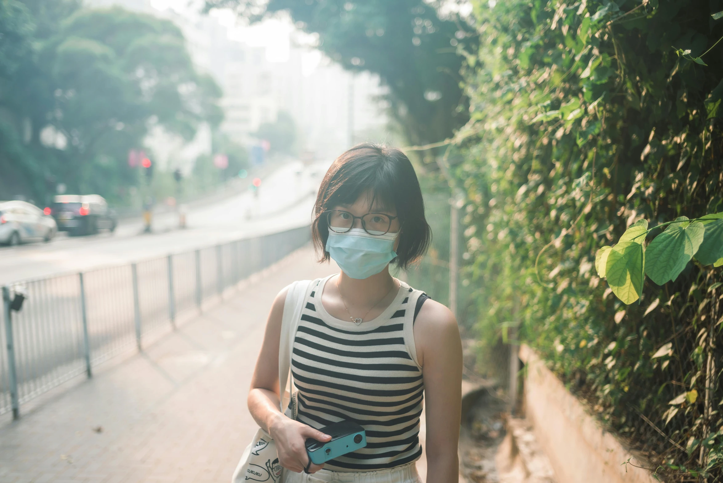 a woman wearing a face mask walking down a street, inspired by Zhang Kechun, trending on unsplash, gemma chan girl portrait, air pollution, a green, avatar image