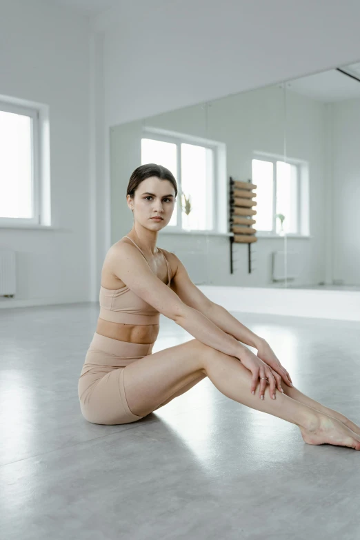 a woman sitting on the floor in a dance studio, a picture, by Nina Hamnett, arabesque, ultra high quality model, soft skin, physical : tinyest midriff ever, katinka reinke