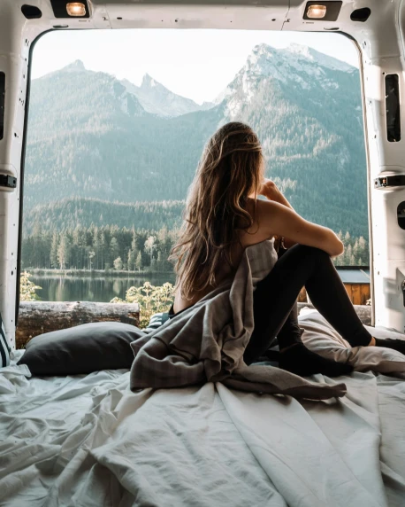 a woman sitting on top of a bed in a van, by Julia Pishtar, trending on unsplash, a mountain look like a women, multiple stories, conde nast traveler photo, cute photo