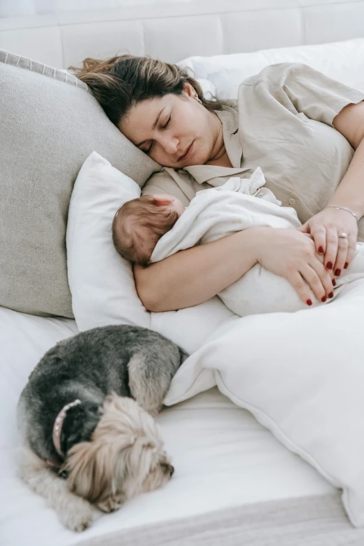 a woman laying on top of a bed next to a dog, babies in her lap, profile image, snoring, manuka