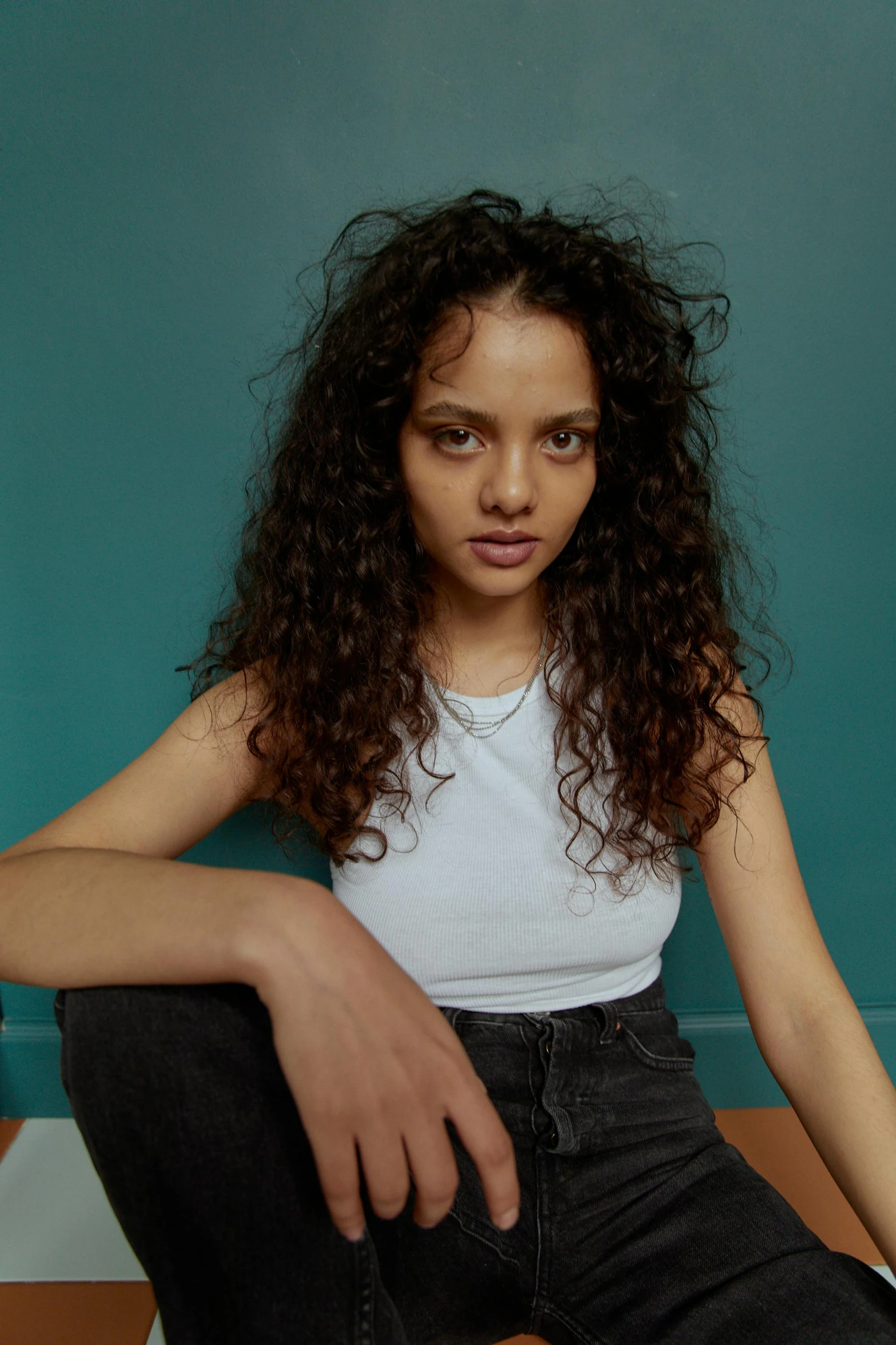 a beautiful young woman sitting on top of a chair, by Winona Nelson, pexels contest winner, renaissance, curly middle part haircut, mixed race, dafne keen, jeans and t shirt