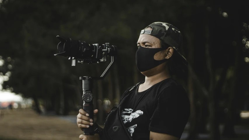 a man wearing a face mask holding a camera, filmic lut, profile picture, action sports photography, avatar image