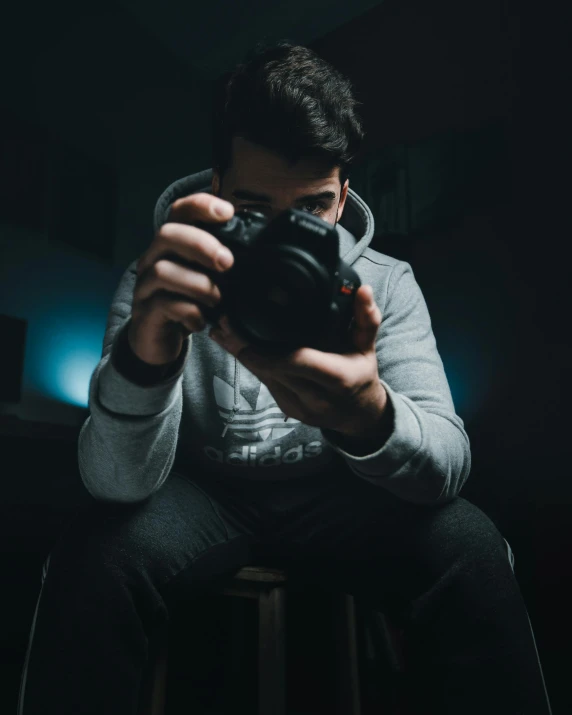 a man sitting on a stool holding a camera, a picture, by Robbie Trevino, low light, discord profile picture, stockphoto, profile picture 1024px