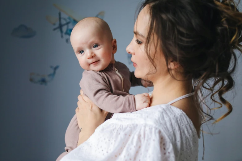 a woman holding a baby in her arms, pexels contest winner, happening, wearing pajamas, bowater charlie and brom gerald, brunette, thumbnail