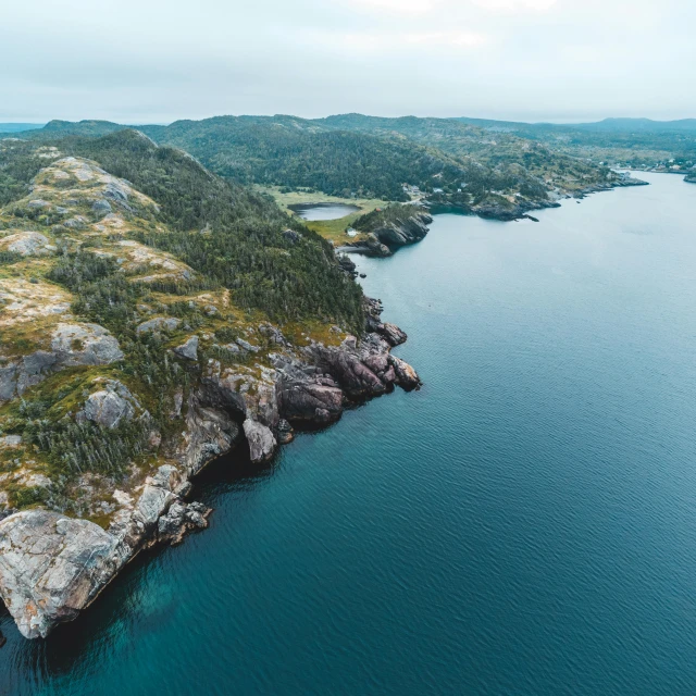 a large body of water surrounded by mountains, by Jesper Knudsen, pexels contest winner, les nabis, rhode island, aerial shot from the drone, hills and ocean, quebec