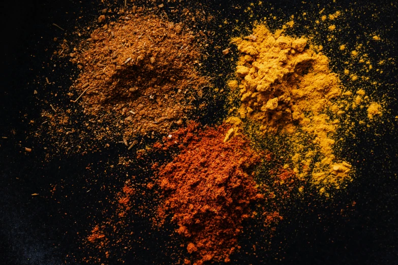 a pile of spices sitting on top of a table, pexels, hurufiyya, black and yellow and red scheme, powder, substance designer, brown