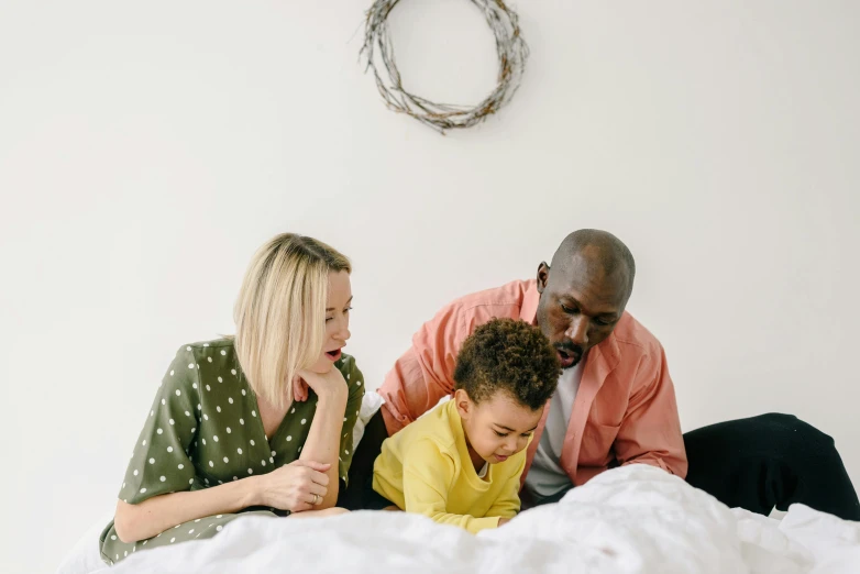 a group of people sitting on top of a bed, by Carey Morris, pexels contest winner, husband wife and son, on a white table, profile image, educational