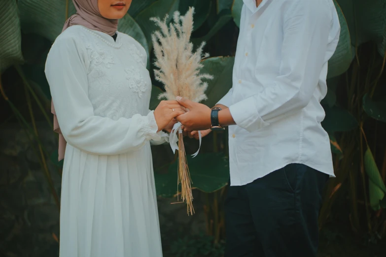 a man and a woman standing next to each other, pexels contest winner, hurufiyya, holding flowers, background image, white sleeves, modestly dressed