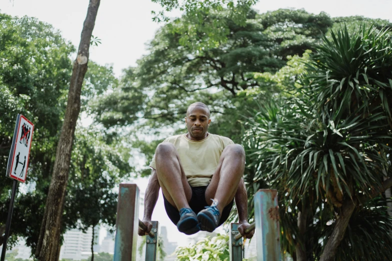 a man sitting on top of a metal pole, a portrait, by Jessie Alexandra Dick, pexels contest winner, at a park, workout, a bald, malaysian