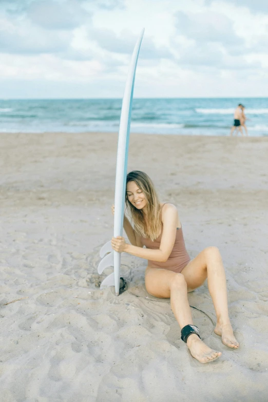 a woman sitting on the beach holding a surfboard, cindy avelino, cute girl wearing tank suit, profile image, tan