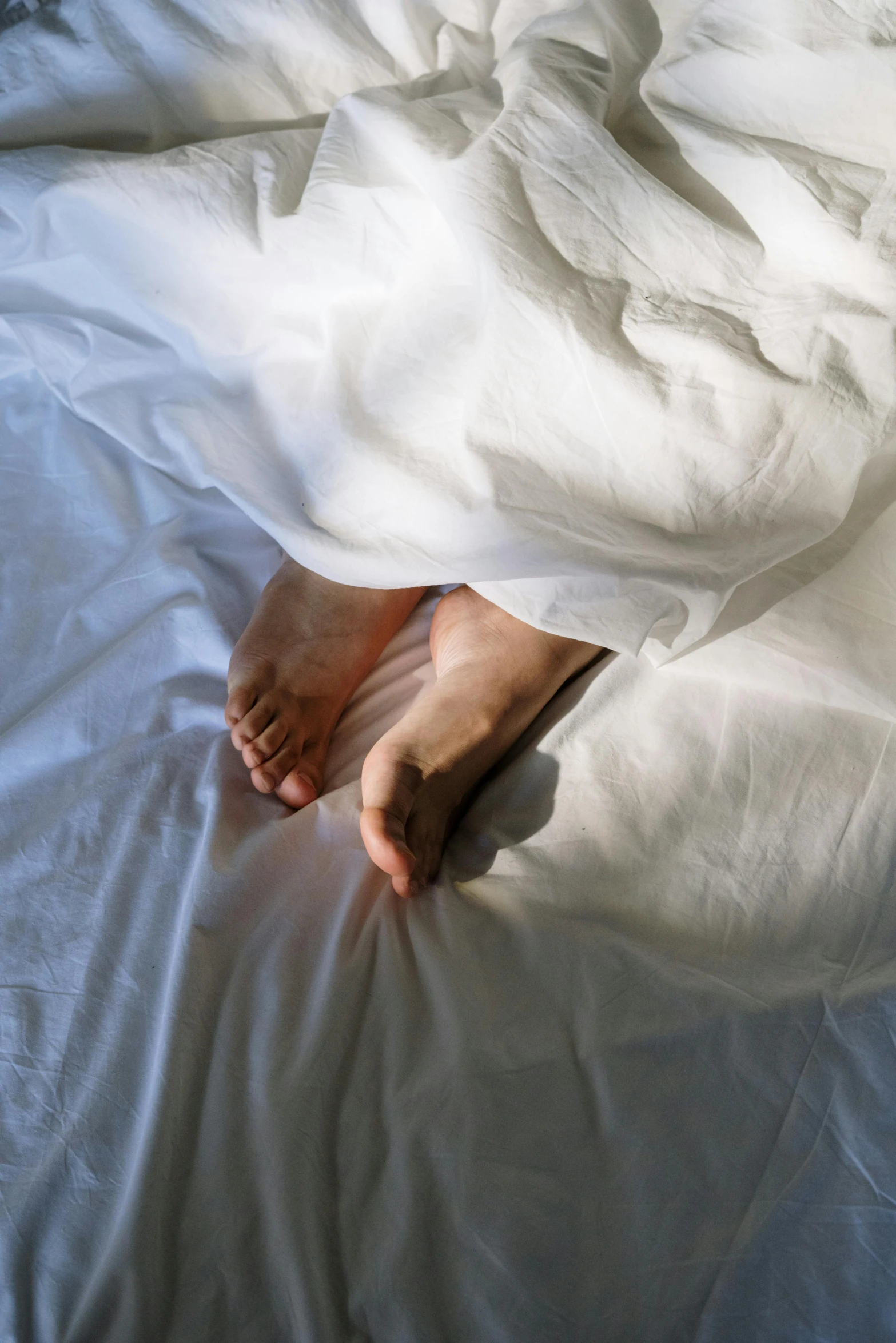 a close up of a person's feet on a bed, pexels contest winner, white cloth in wind shining, asleep, making love, high shadow
