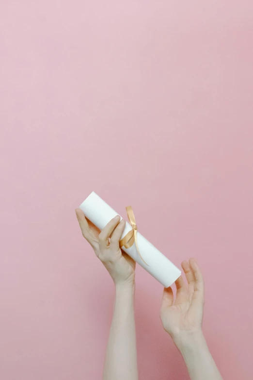 a woman holding a diploma in front of a pink wall, pexels contest winner, minimalism, porcelain organic tissue, chocolate candy bar packaging, elegant hand, scrolls